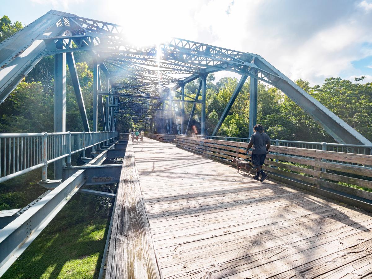 Man Walking Dog Across Bridge