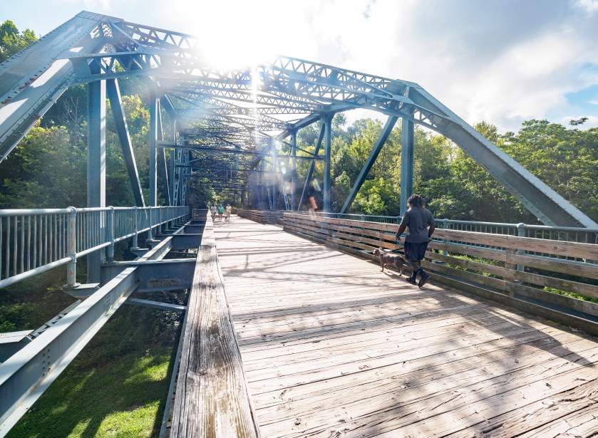 Man Walking Dog Across Bridge